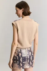 Chaleco sin mangas de viscosa, con escote en V y largo a la cintura. El frente cuenta con un panel de lentejuelas con estampado animal print de serpiente, mientras que la espalda y los bordes son de tejido liso en color tostado.