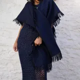 Chal de tejido liviano con terminaciones desflecadas en los bordes, ideal para usar como capa o accesorio versátil.