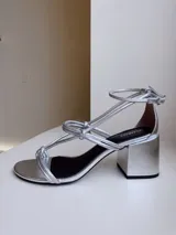 Sandalias plateadas de cuero nobuk, con tiras finas cruzadas en el empeine y tobillo, ajuste de pulsera y taco cuadrado de 7 cm.