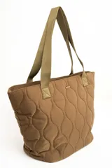 Bolso tipo tote bag color marrón con diseño capitonado de ondas, asas largas y placa metálica con el logo de la marca.
