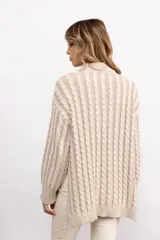 Sweater de tejido de punto con diseño de trenzas verticales, cuello alto, manga larga y silueta oversize de largo extendido.