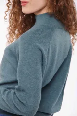 Sweater de punto color verde azulado, con cuello alto y mangas largas.