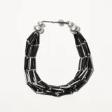 Collar corto de cuentas tubulares negras y plateadas, con esferas plateadas en los extremos.