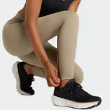 Calza deportiva de tiro alto, color beige, ajustada al cuerpo, con banda elástica en la cintura que lleva el logo de New Balance.