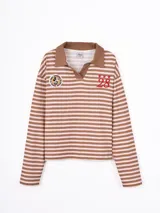 Remera de manga larga estilo polo a rayas horizontales en tonos camel y blanco, con cuello camisero en contraste y parches bordados en el pecho.