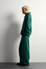 Pantalón jogger de corte relajado y pernera ancha, confeccionado en tejido de algodón con interior perchado. Cuenta con cintura elástica ajustable mediante cordón interior, bolsillos laterales y un bolsillo trasero de plastrón.