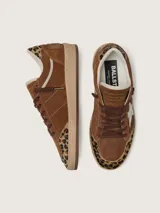 Zapatillas Golden Goose modelo Ball Star, confeccionadas en gamuza marrón con detalles en animal print de leopardo en la puntera y el talón. Presenta la característica estrella lateral en cuero crema, cordones marrones y suela de goma camel.