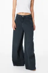 Jean de corte wide leg en color negro lavado, con tiro medio y cierre de botón y cremallera. Presenta bolsillos traseros amplios y etiqueta de cuero sintético con el logo de la marca en la parte posterior.