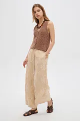 Pantalón ancho de poliéster color beige con diseño bordado floral en hilo blanco, cintura elastizada con cordón ajustable.