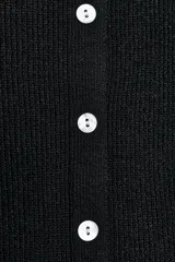 Top de punto acanalado en color beige, sin mangas y con cuello redondo. Presenta un cierre frontal con botones pequeños y un bajo con acabado en peplum que aporta volumen.