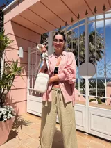 Bandolera compacta color rojo con textura de cuero, correa regulable y desmontable con diseño de rayas rojas y blancas. Cuenta con bolsillos frontales y cierre, interior forrado en tela.