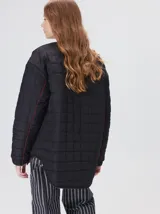 Campera reversible capitoneada con cierre frontal. Un lado es de color negro y el otro es de color beige, ambos con diseño acolchado. Cuenta con cuello redondo, mangas largas y bolsillos laterales.