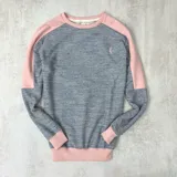 Buzo gris con mangas y cuello rosado claro, confeccionado en algodón rústico.