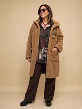 Chaquetón de textura tipo peluche, color tostado, con diseño de corte recto, cuello con solapas, mangas largas y bolsillos frontales aplicados.