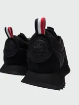Zapatillas Moncler modelo Pacey de color negro, con diseño de caña baja y suela dentada. Presentan detalles en gamuza y nylon, y una presilla trasera con los colores tricolores de la marca.