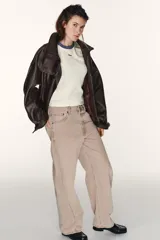 Jeans de tiro medio, color beige rosado con efecto lavado, corte amplio (baggy balloon) y detalle de costuras torcidas en el frente de las piernas.