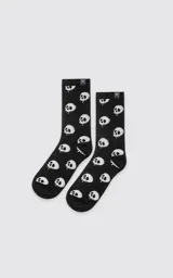 Medias negras con estampado de calaveras blancas en contraste, tiro medio con ribete elástico y pequeña etiqueta con el logotipo de unas tijeras en el borde superior.