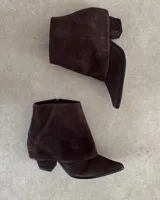 Botinetas de gamuza color marrón, con diseño de caña solapada y taco cuadrado bajo. Presentan punta fina y suela negra.