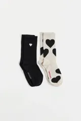 Pack de dos pares de medias de caña media, una en color negro con pequeño corazón blanco bordado y otra en color crema con estampado de corazones negros. Ambas cuentan con el logo de la marca bordado en el pie.