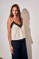 Blusa satinada marrón con detalles de encaje en el escote en V y en el ruedo. Presenta tirantes finos regulables.