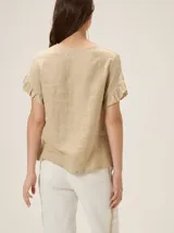 Blusa de lino color rosado, de corte recto y holgado, con cuello redondo y mangas cortas adornadas con volados.