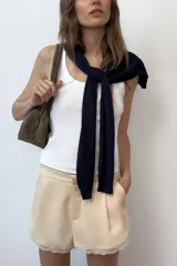 Shorts de tiro medio confeccionado en tejido satinado, con pinzas en el delantero, bolsillos laterales y detalle de encaje a tono en el ruedo. Cuenta con cierre frontal mediante cremallera, botón interior y gancho metálico.
