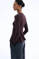 Top de manga larga en punto de crepé, con cuello redondo y diseño con peplum. Presenta costuras moldeadoras en la parte frontal y posterior que definen la silueta.