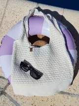 Bolso de hombro tejido a crochet en hilo color crudo, con diseño calado y asas trenzadas.