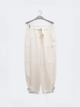 Pantalón estilo cargo de color marrón, confeccionado en una mezcla de lino y lyocell. Presenta cintura elástica con cordón ajustable, bolsillos laterales tipo parche y detalle de botones en los tobillos para un ajuste opcional.