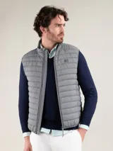 Chaleco acolchado de hombre color gris, con diseño matelasseado horizontal, cuello alto y cierre frontal completo. Presenta un calce ajustado y detalle de logo circular bordado en el pecho.