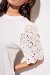 Remera de algodón peinado color negro, con mangas cortas de broderie con diseño calado y terminación festoneada. Presenta un corte oversize y cuello redondo.