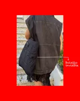 Bolso tipo tote de diseño urbano, confeccionado en material impermeable acolchado de color negro. Cuenta con doble asa de hombro, compartimento principal con cierre, bolsillo frontal con cierre y detalle de logo circular en la parte superior.