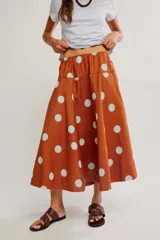 Falda midi de corte A y cintura baja, confeccionada en popelina de algodón color marrón terracota con estampado de lunares celestes.