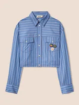 Camisa corta celeste a rayas blancas con bordes sin rematar, bolsillos de parche con solapa y pines removibles con motivos de Jamaica.