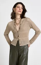 Cárdigan de punto beige con diseño calado y texturizado. Presenta cuello redondo, mangas largas y cierre frontal con botones a tono.