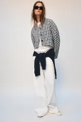 Chaqueta corta de Zara Woman Collection confeccionada en tejido de algodón con estampado de cuadros en tonos blanco, azul y negro. Presenta escote en pico, manga larga y cierre frontal con botones oscuros.