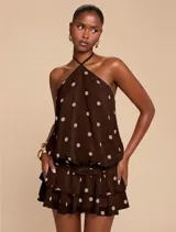 Vestido corto marrón con estampado de lunares beige, diseño sin mangas, cuello halter y falda con volantes escalonados.