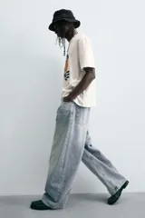 Jeans de denim de algodón, color azul oscuro con efecto lavado. Presentan un corte muy holgado (baggy fit) en toda la pierna y tiro medio. Tienen cinco bolsillos y cierre frontal con cremallera y botón.