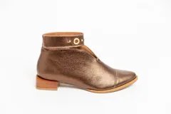 Botín de cuero color borgoña con taco bajo, corte en V en el empeine, pulsera con detalles metálicos y cierre lateral.