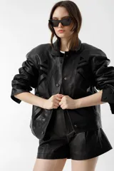 Chaqueta negra de cuero de oveja con apliques tribales en gamuza de cabra al tono, forro capitoneado de poliéster, cuello camisero redondeado, bolsillos frontales, bolsillo interno y botones metálicos a presión forrados.