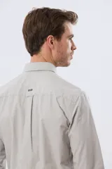 Camisa celeste de manga larga confeccionada en algodón, con cuello camisero, cierre frontal de botones, bolsillo en el pecho y diseño de cuadros sutiles.