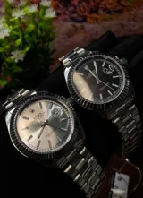 Reloj de pulsera para hombre con diseño clásico Datejust, esfera plateada con función de calendario y lupa, bisel estriado y brazalete metálico de eslabones tipo Jubilee.