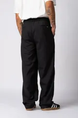 Pantalón sastrero de corte baggy, color beige, con pinzas frontales, cierre de botón y cremallera, y bolsillos laterales.