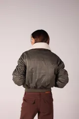 Campera bomber verde militar con cuello de corderito desmontable, cierre frontal y puños y ruedo elastizados.