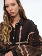 Camisa larga de diseño patchwork con cierre frontal de botones, confeccionada en una combinación de texturas lisas y estampados florales con detalles bordados en el canesú y los puños.