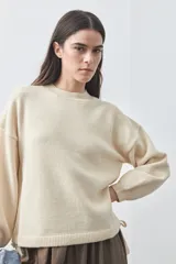 Sweater de tejido liviano con silueta relajada, hombros caídos y mangas largas con puños ajustados. Presenta cuello redondo y lazos ajustables en el bajo.