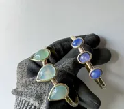 Pulsera rígida de bronce color dorado con tres piedras de ágata blancas de forma ovalada.