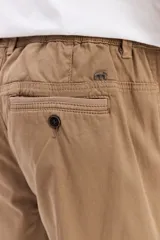 Pantalón cargo color tostado de corte amplio, con cintura elástica y cordón ajustable. Cuenta con bolsillos laterales con tapa en las piernas y puños elastizados en los tobillos.