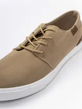 Zapatilla urbana de gamuza sintética color gris, con cordones oscuros, suela de goma blanca y detalles en cuero sintético color suela en el talón y lateral.