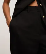 Pantalón de vestir color marrón, de corte recto y tiro alto, con cierre frontal y bolsillos delanteros.